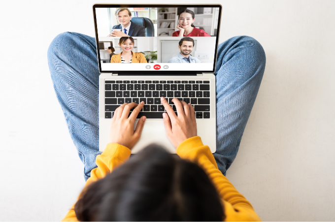 Eine junge Frau sitzt im Schneidersitz
mit ihrem Laptop auf dem Schoß. Auf
dem Bildschirm ist ein virtuelles
Video-Gespräch mit vier Personen zu
erkennen.