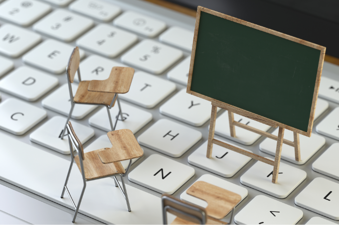 Auf einer Tastatur stehen eine
Miniatur-Tafel und drei Miniatur-
Stühle, was an einen Ort des Lernens
erinnert.